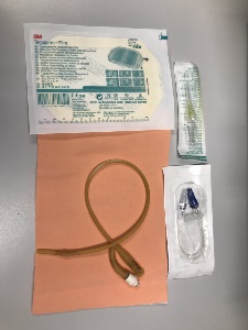 tegaderm in packaging, angiocatheter in packaging, IV extension tube in packaging, latex urinary catheter on top of simulated skin