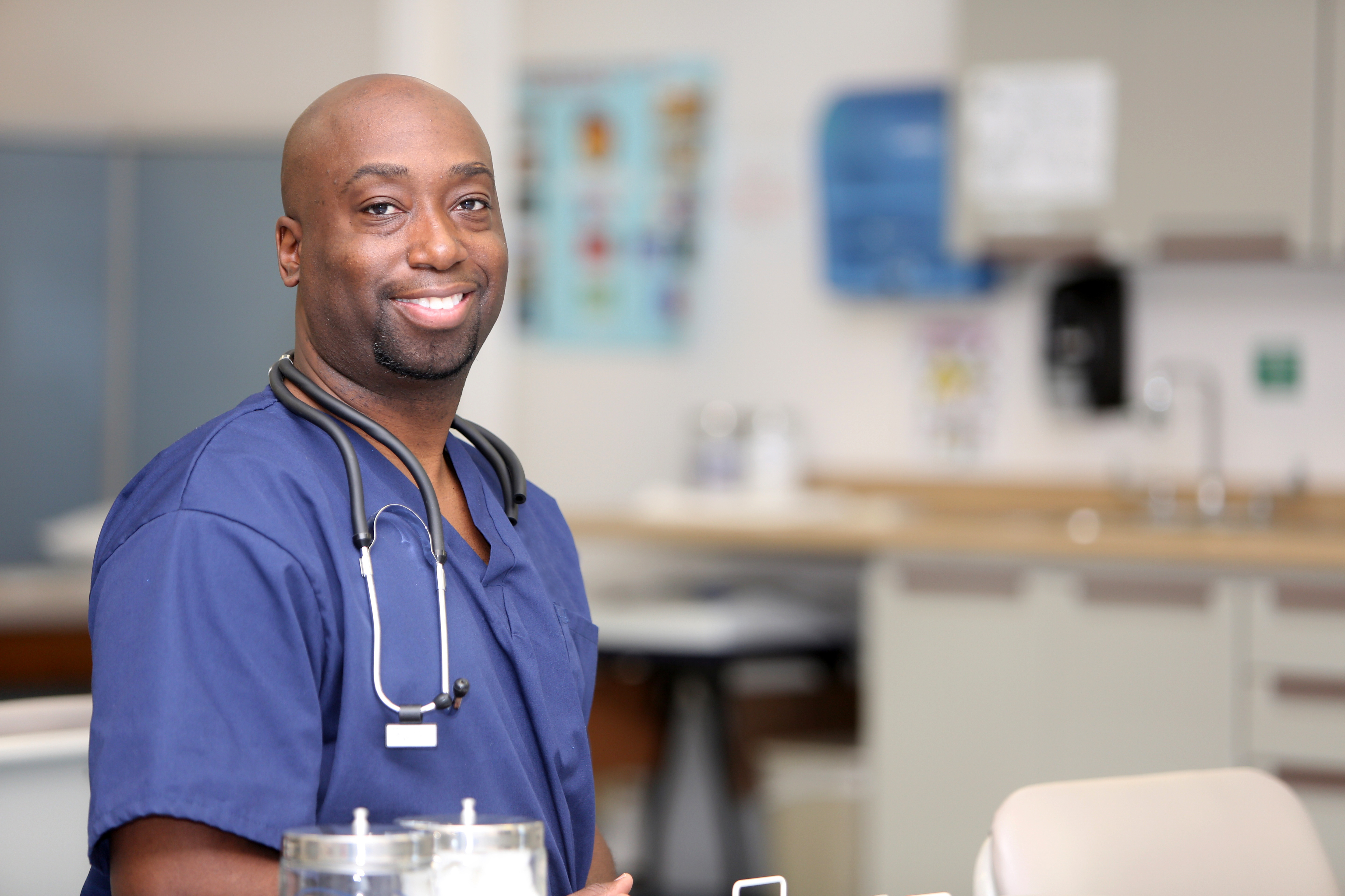 Smiling nurse with dark skin in blue scrubs