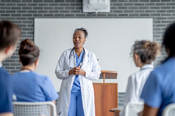 A nurse educator speaks in front of a classroom.