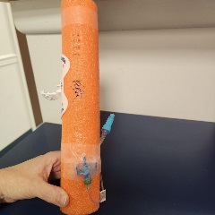 12-inch section of orange pool noodle with staples, sutures, IV extension lock, and statlock
