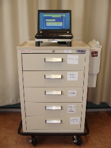 beige medical cart with five drawers on wheels with a laptop on top