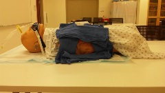 intubated manikin in hospital gown draping to expose the side of the torso with pig skin