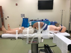 intubated full size pregnant manikin strapped to gurney
