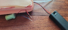 Close-up of threaded through the hole in the side of the IV trainer so that the battery pack is on the outside