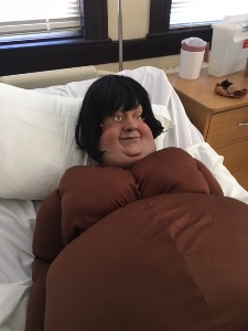 manikin with a caricature obese mask in a hospital bed wearing a obesity suit