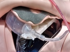 JP drain with tubing connected underneath the distal end of the chest plate alongside manikin's left chest rise bladder with tubing pointed towards the left side of the chest