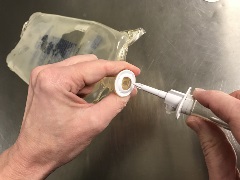 inserting IV tubing spike into empty IV bag