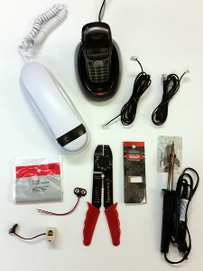 a white corded phone, a black cordless phone, two phone cords, a soldering iron, flux wire, wire stripper, 9V battery snap connector, and phone line coupler