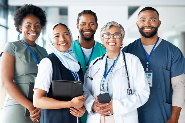 Smiling group of people in scrubs and street clothes.