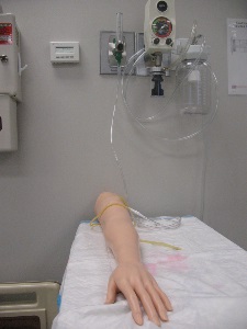 manikin arm with IV tubes draining pink liquid on disposable underpad