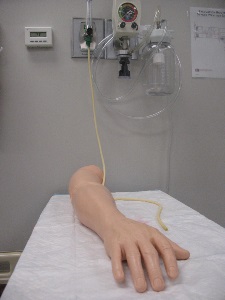 manikin arm with IV tubes attached to O2 wall device