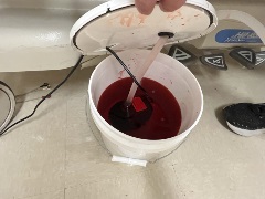 five gallon bucket with attached aquarium pump half filled with simulated blood