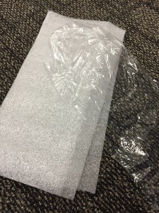 two pieces of thin foam and a piece of plastic food wrap