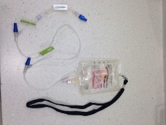 J-loop with IV extension tubing and empty IV fluid bag attached. IV bag has a lanyard attached.