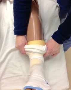 person putting an anti-embolism stocking over a piece of memory foam on a manikin lower leg