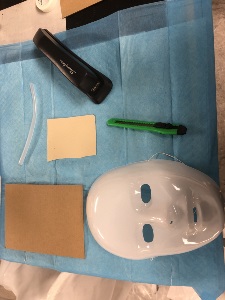 "5 X 7" corrugated cardboard sheet, 6mm X 8mm silicone tube, white plastic full-face Halloween mask, scrap paper, utility knife, and stapler