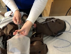 person holding a large volume enema bag with salem sump/NG tube attached over an open chest cavity of a manikin