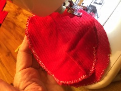 two red fabric ovals in a sewing machine being stitched together